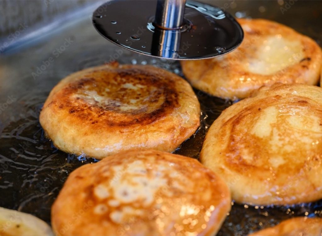 Hotteok ,sweet pancakes frying on a griddle with melted brown sugar filling